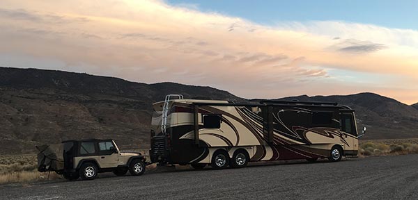 A picture of Tracey’s RV in the foreground and a beautiful mountain range and sunset in the background